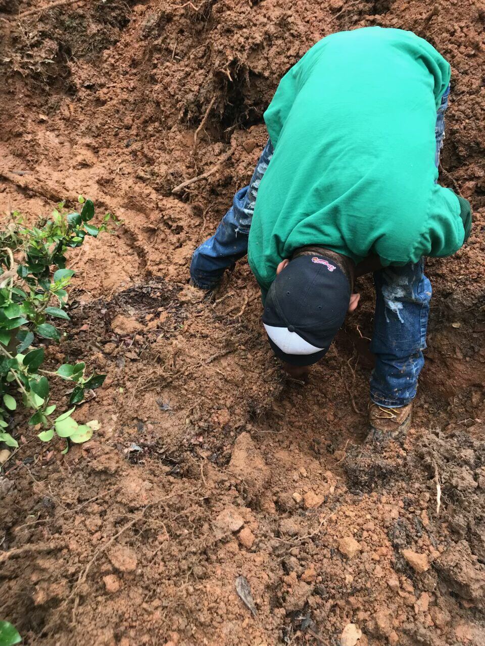 Plumber hand digging to expose a damaged underground pipe
