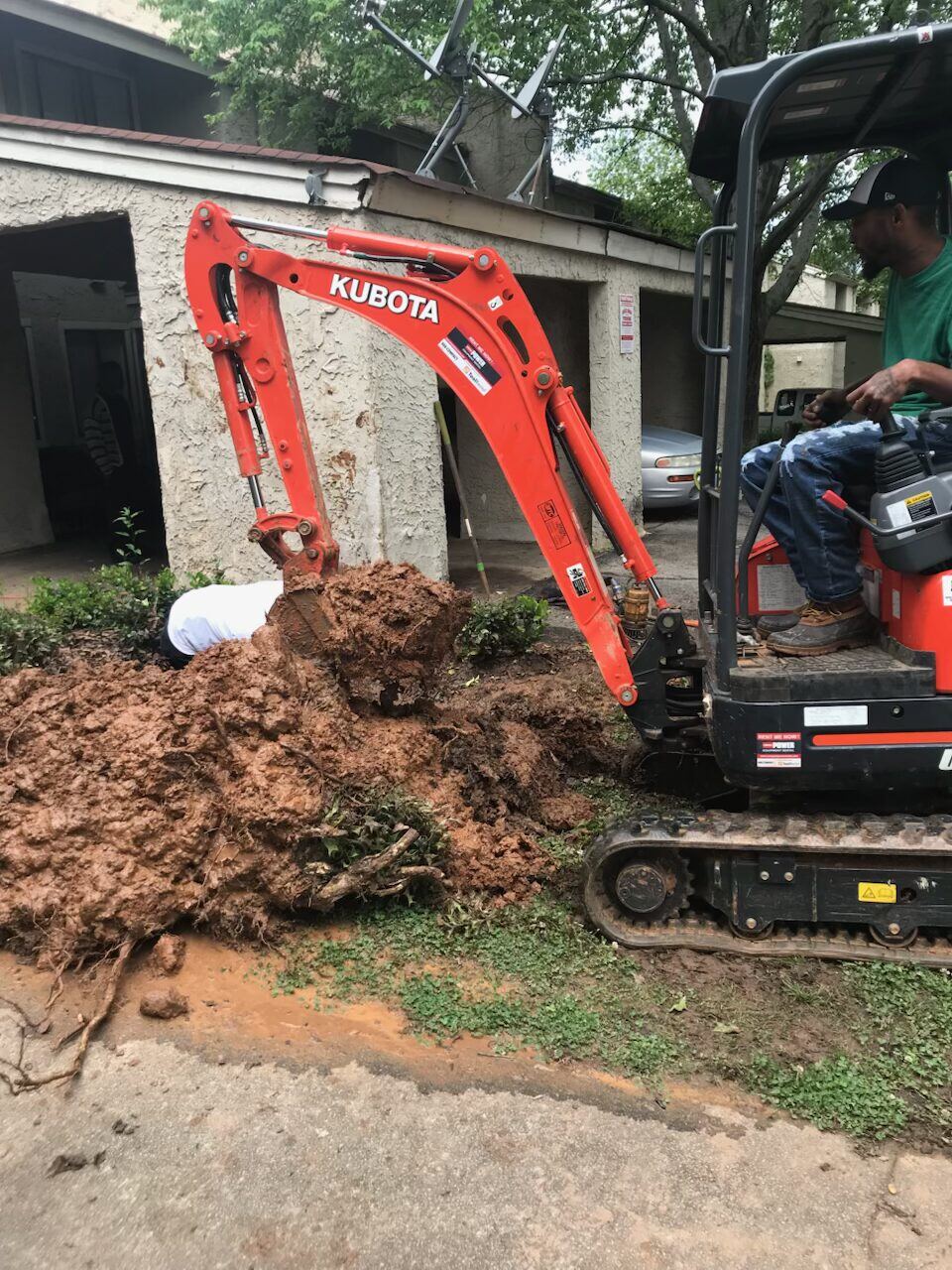Excavator digging beside a driveway during a water main repair