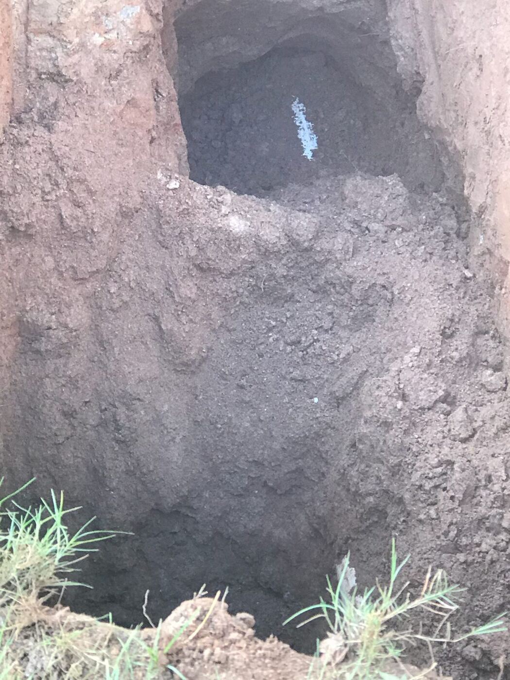 Open excavation exposing a repaired underground pipe connection