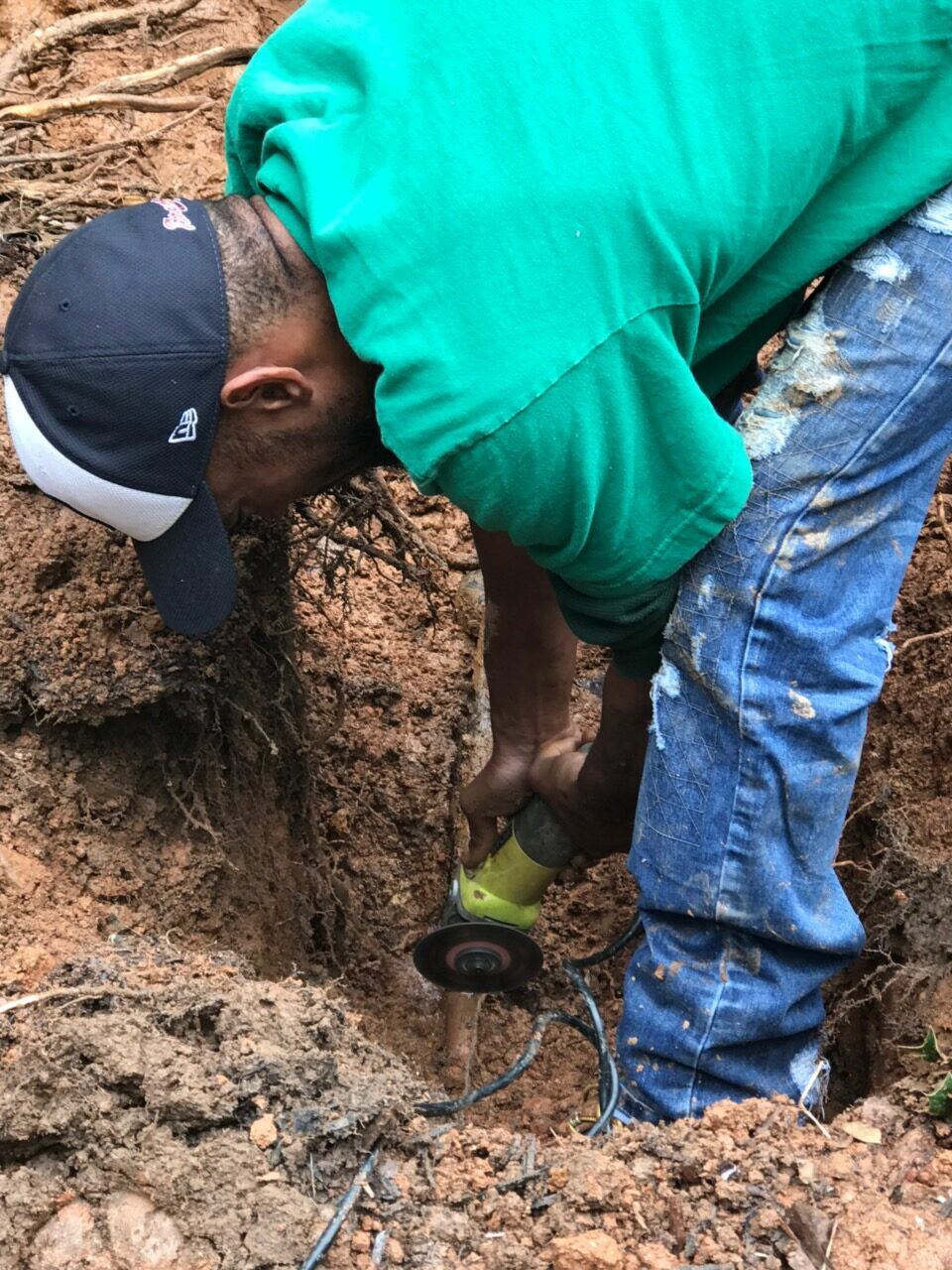 Technician working down in a trench on a damaged sewer pipe