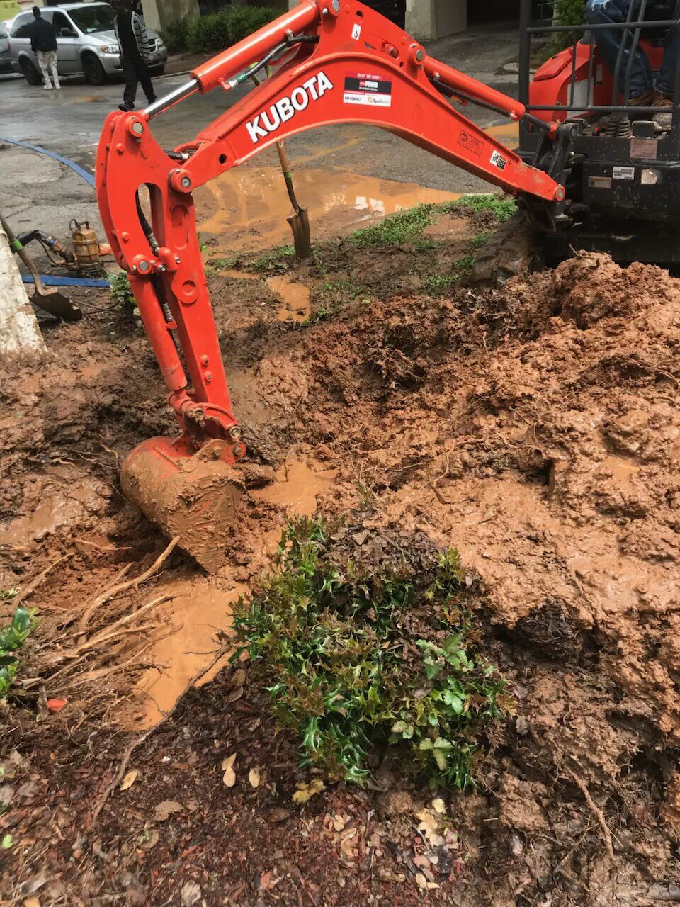 Mini excavator bucket lifting Georgia clay out of a sewer line trench